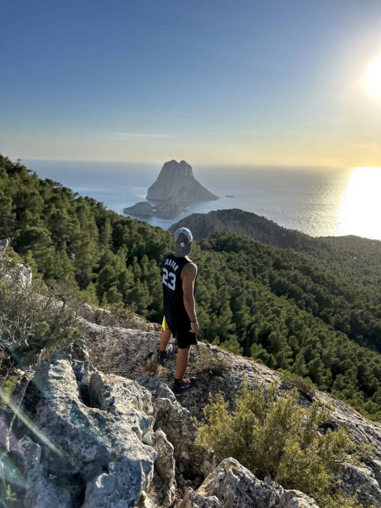 Hiker enjoying panoramic view of Es Vedrà island during Mystical Hike Station coastal hike in Ibiza at sunset