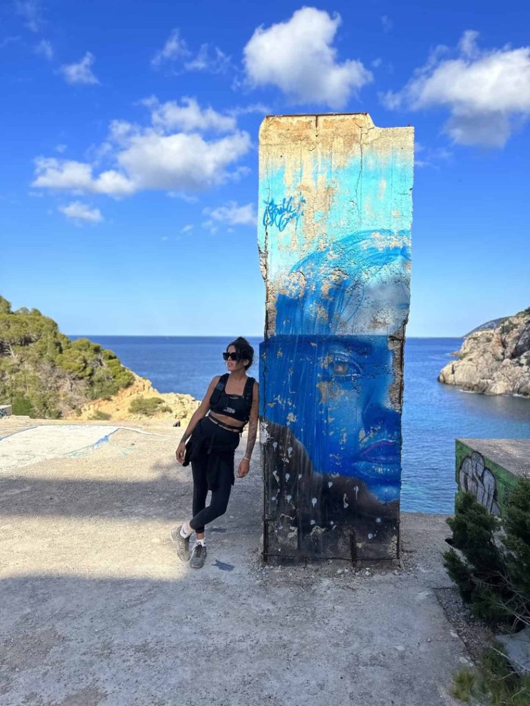 Hiker by colorful seaside graffiti art with stunning sea view during Azure Hike Station coastal hike in Ibiza