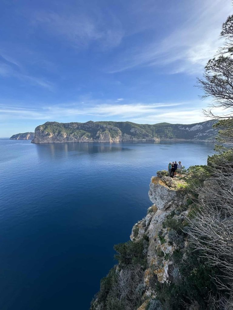 Hikers standing on a cliff viewpoint above Ibiza’s dramatic fjord coastline on the scenic Fjord Hike Station trail