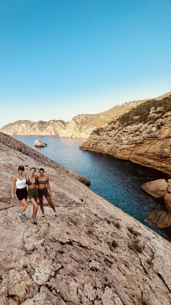 Three hikers on rocky cliffs above a turquoise Ibiza cove during the scenic Jewel Hike Station coastal adventure