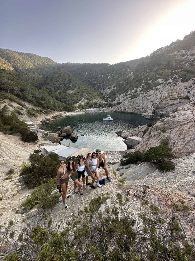 Guided hiking group overlooking a hidden turquoise cove and cliffs on Ibiza’s scenic Jewel Hike Station coastal trail