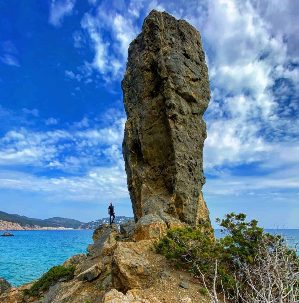 Hiker standing by dramatic coastal rock pillar during tailor-made guided hiking adventure in Ibiza