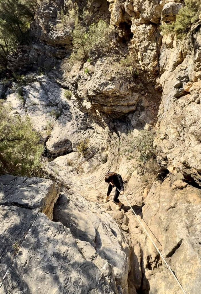 Hiker walking along rocky beach with sea stacks during Beach Hike Station coastal hiking adventure in Ibiza