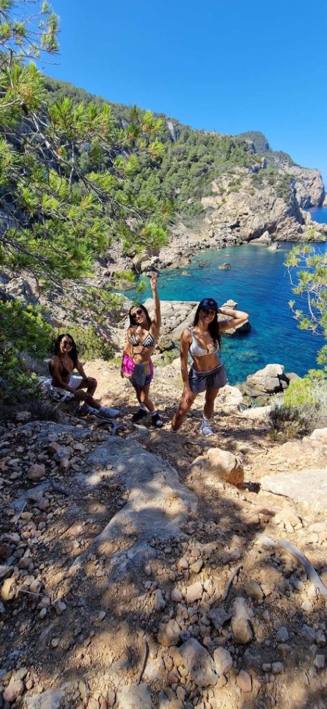 Hikers above a turquoise lagoon and cliffs on Ibiza’s scenic Lagoon Hike Station coastal trail.