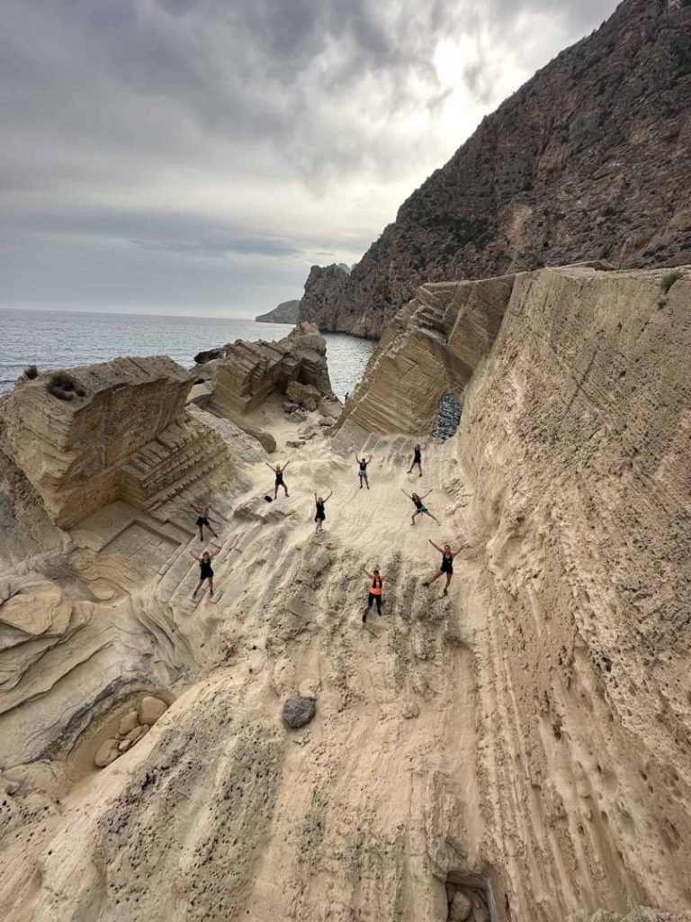 Group of hikers exploring uniquely carved sandstone cliffs on Ibiza’s Legend Hike Station coastal adventure trail