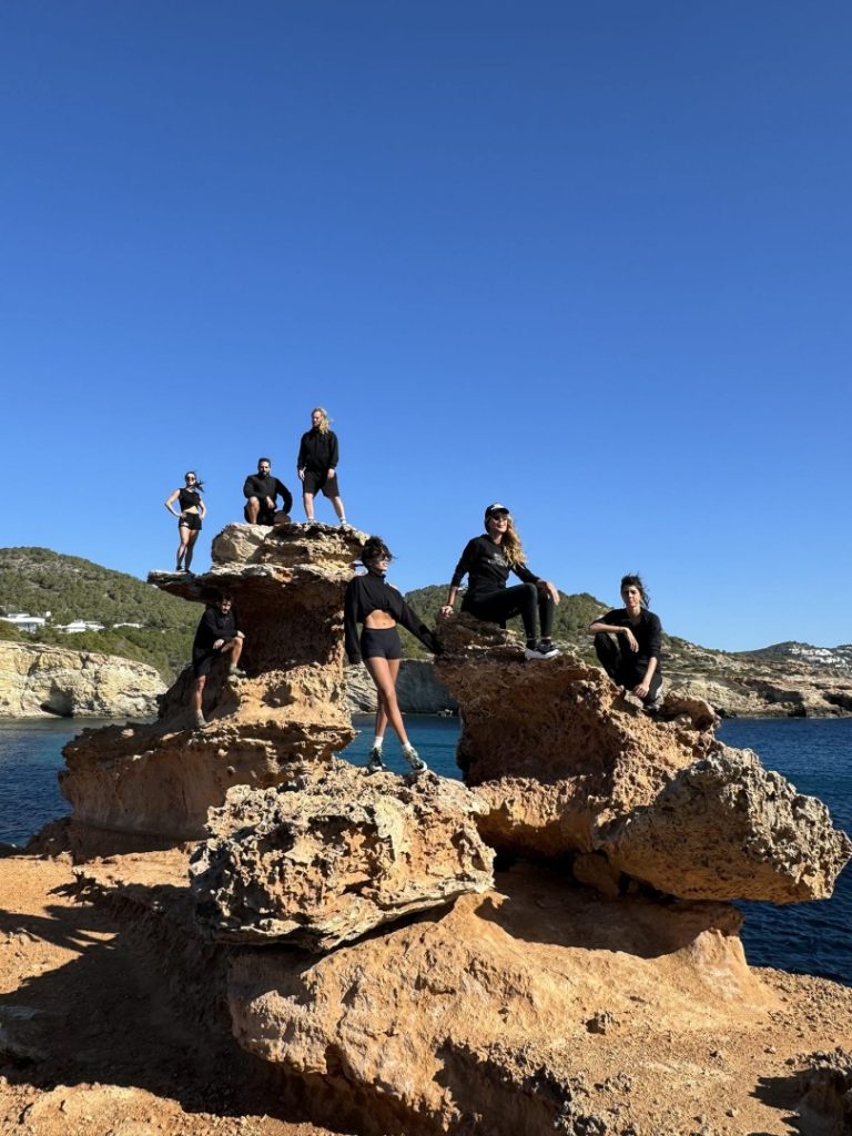 Group of hikers posing on coastal rock formation during Nobu Hike Station scenic coastal hike in Ibiza