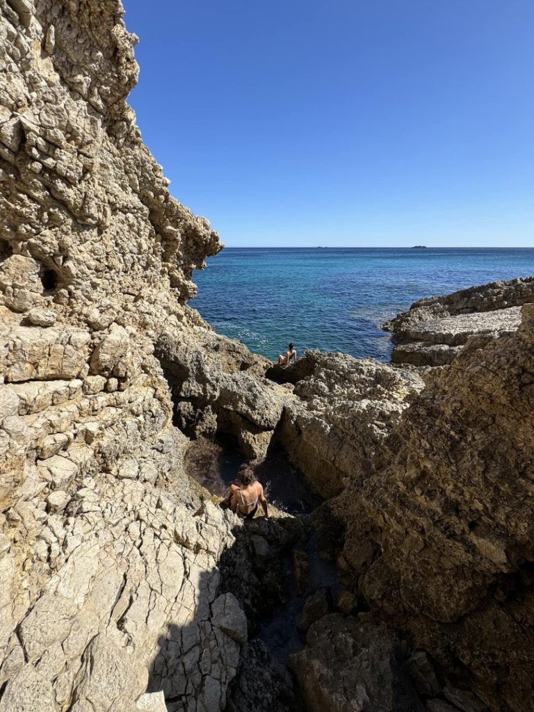 Hikers exploring rocky sea cave and natural pools during Nobu Hike Station coastal hiking adventure in Ibiza