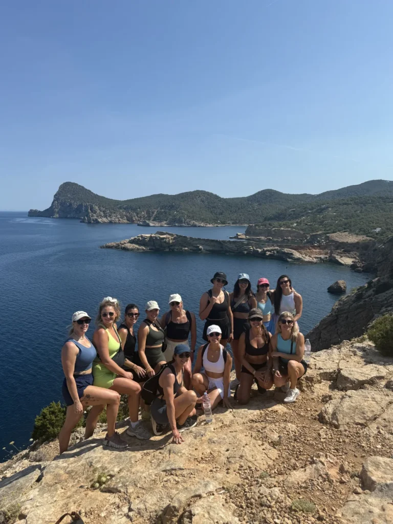 Group posing for a picture in front of a stunning coastline on OKU Hike Ibiza